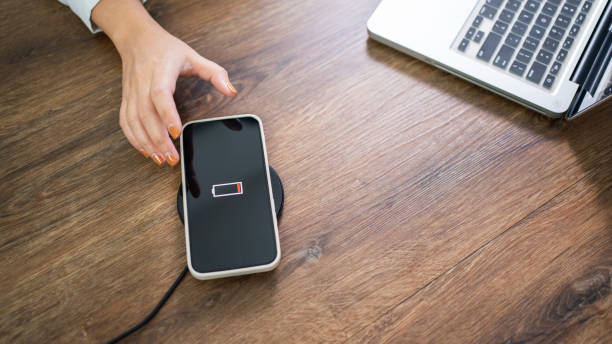 istock Charging mobile phone battery with wireless charging device in the table. Smartphone charging on a charging pad. Mobile phone near wireless charger Modern lifestyle technology concept. 1575831580