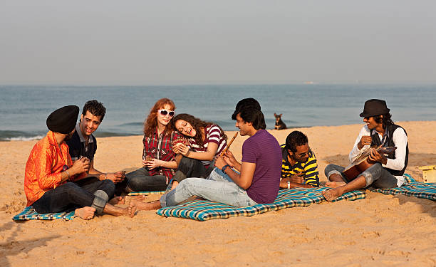 Good time on the beach in India 7 young people having fun on the beach, playing cards and doing some jamming on guitar and flute. beach goa party stock pictures, royalty-free photos & images