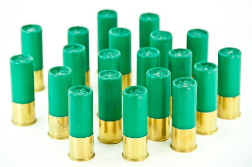 Several green 12 gauge shotgun shells on a white background. Copy space and front view.