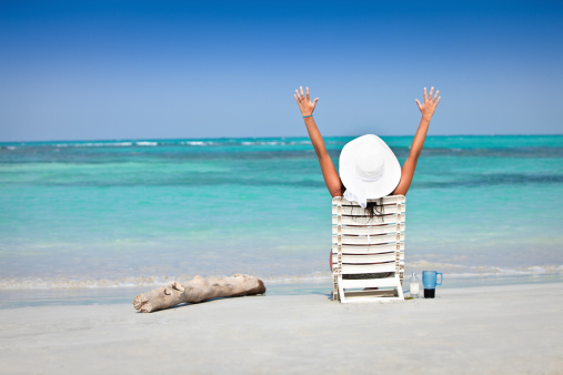 Young woman sunbathing and relaxing on chair in a Tropical white sand island beach