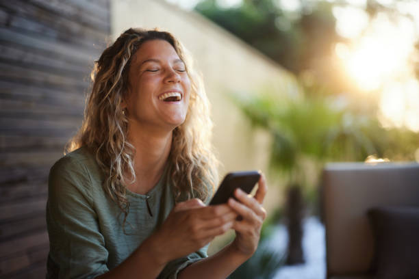 istock Cheerful woman having fun while using cell phone on a patio. 1575837115