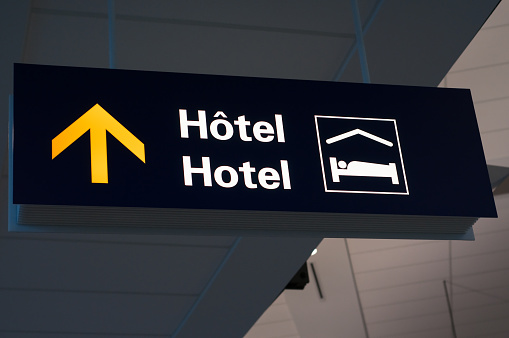 Bilingual French and English airport hotel sign with international lodging symbol.