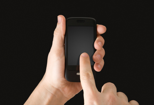 A generic touchscreen device being held in one hand while the other touches the screen. The screen is well suited for content such as text messaging, surfing the web or playing video games. With clipping path.
