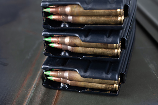 5.56�45mm cartridges with standard lead core bullets with steel penetrator loaded in magazines on green ammo box