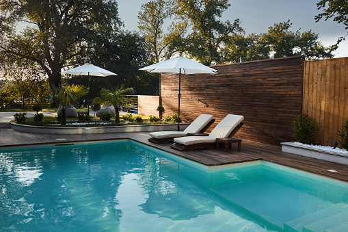 Sunglasses and straw hat on the wooden floor at the pool. Summer Vacation Fashion Concept.