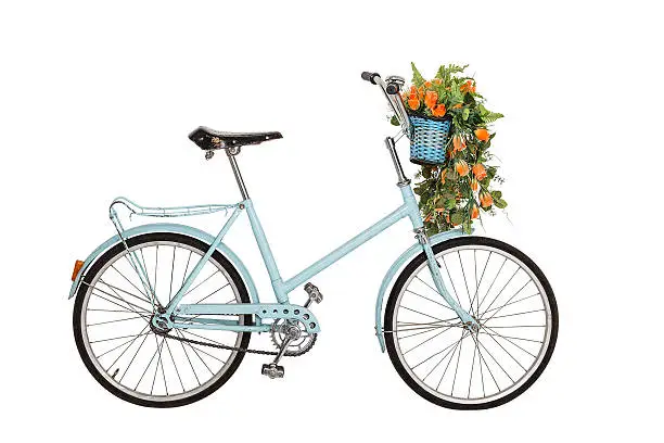 Old retro blue bicycle with flowers bouquet in basket isolated on white background