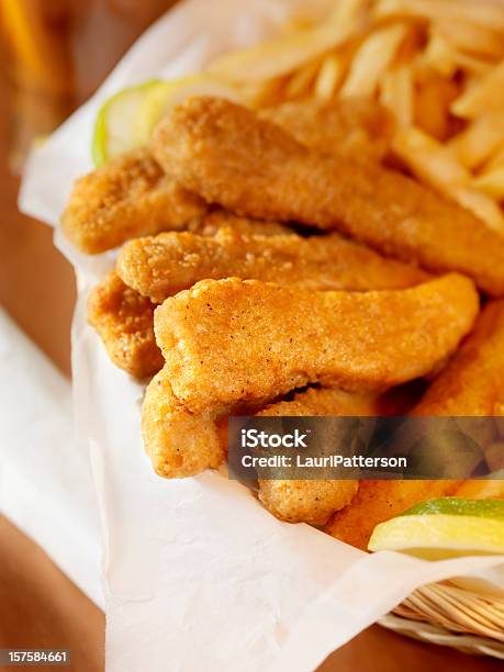 Tiras De Pollo Con Papas Fritas En Una Cesta Foto de stock y más banco de imágenes de Fritura - Fritura, Pollo, Nugget de pollo