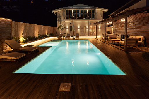 Vacation house with swimming pool and modern backyard at night.