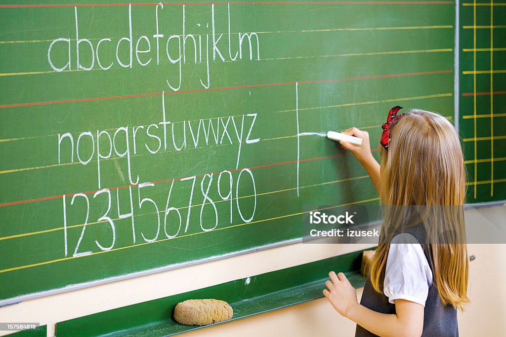 School Girl Writing On Blackboard, Close Up A school girl writing on a blackboard with a white chalk. 6-7 Years Stock Photo