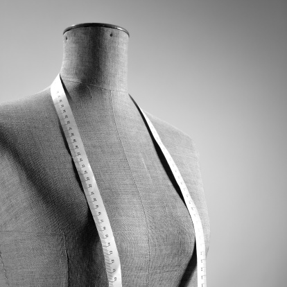 Close-up of retro female tailor's mannequin torso with measuring tape around neck. Copy space, black and white picture.