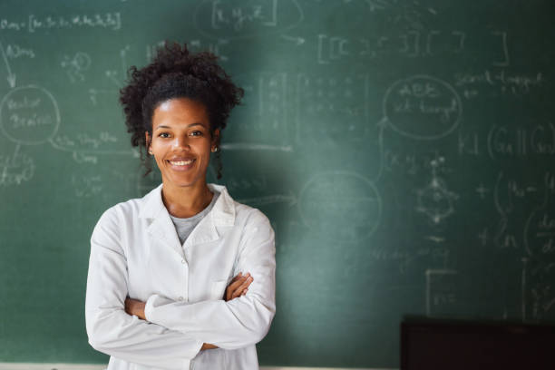 istock Happy black scientist against blackboard with crossed arms. 1575853968