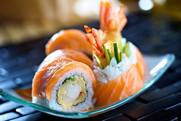 Close-up photo of Futomaki sushi on a blue plate Big futomaki sushi with salmon, prawn tempura and cucumber maki sushi stock pictures, royalty-free photos & images