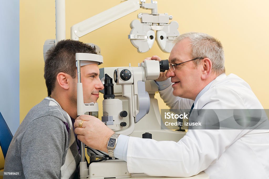 Optometrist Eye Exam Tonometer Optometrist examines the eyes of a young man patient with a tonometer. Eye Exam Stock Photo