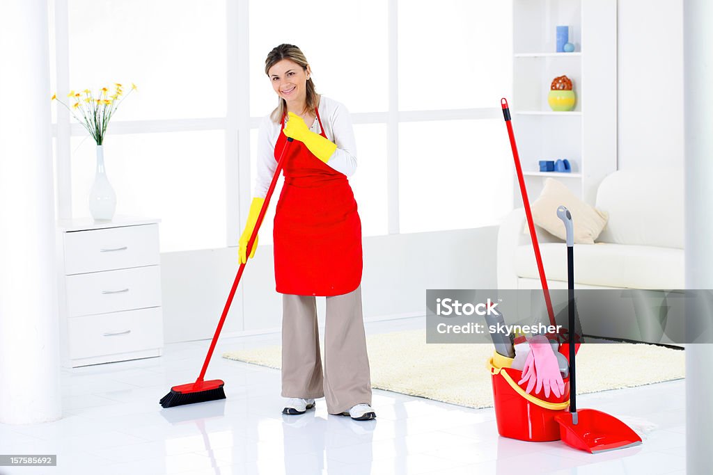 Charwoman sweeping a room. Charwoman sweeping a floors in the room. Adult Stock Photo
