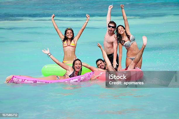 Foto de Grupo De Jovens Com Boias Flutuando Em Uma Praia e mais fotos de stock de Adolescente - Adolescente, Adolescência, Alegria