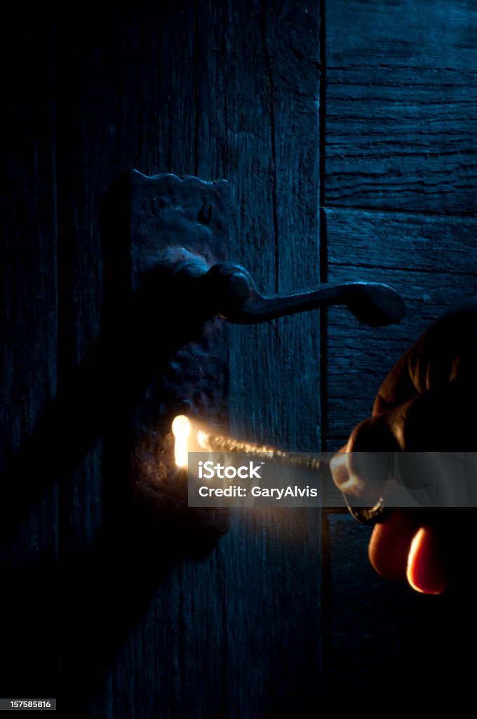 Mysterious Lock and key-light coming through keyhole Mysterious door exterior under blue light with a golden ray of light emanating from the keyhole from the other side, lighting a skeleton key being held by an unknown stranger.http://www.garyalvis.com/images/conceptsIdeas.jpg Key Stock Photo