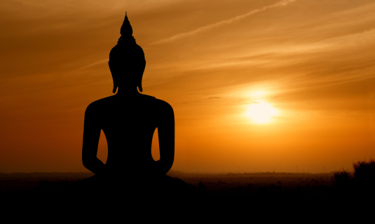 Silhouette of Buddha mediating in the twilight with sunrise background. Magha Puja, Asanha Puja, and Visakha Puja Day. Buddhist holiday Concept.