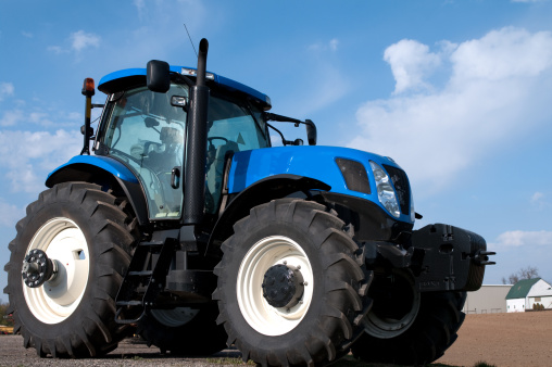 A new blue farm tractor against a cloudy blue sky.