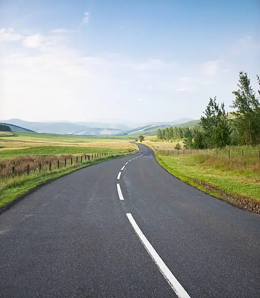 A curving, quiet road in the rolling countryside of the Scottish Borders.