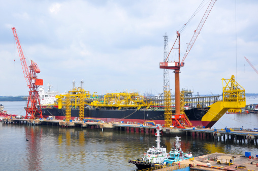 Construction of an FPSO vessel (Floating Production, Storage and Offloading) at a dockyard.  FPSO is used in the oil & gas industry - deployed to process offshore oil and gas, and stores them until the oil & gas can be offloaded onto shuttle tankers, or sent through a pipeline.
