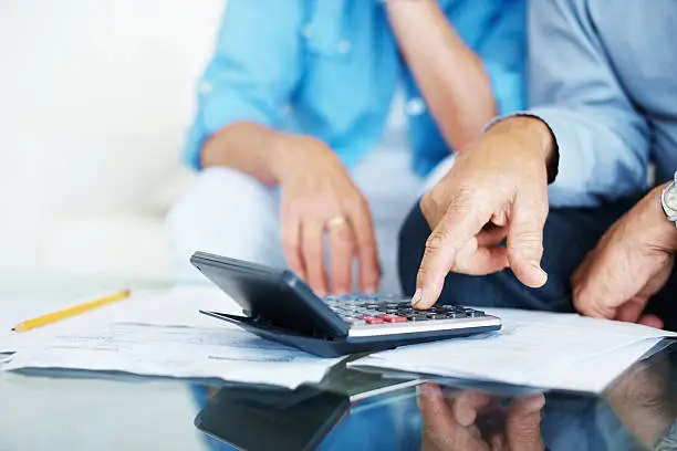 Photo of Closeup of old man's hand calculating bills at home