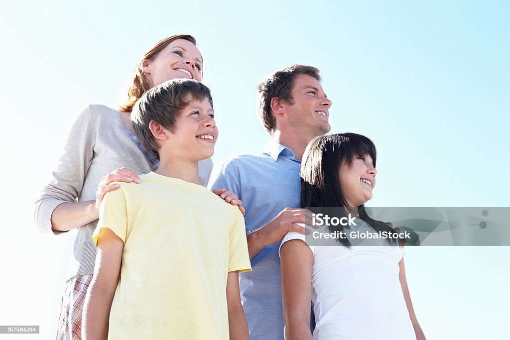 Famiglia felice di quattro contro il cielo azzurro - Foto stock royalty-free di 10-11 anni