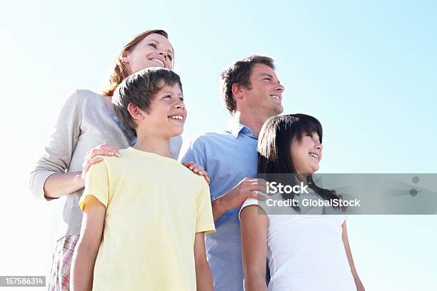 Famiglia Felice Di Quattro Contro Il Cielo Azzurro - Fotografie stock e altre immagini di 10-11 anni - 10-11 anni, 8-9 anni, Abbigliamento casual