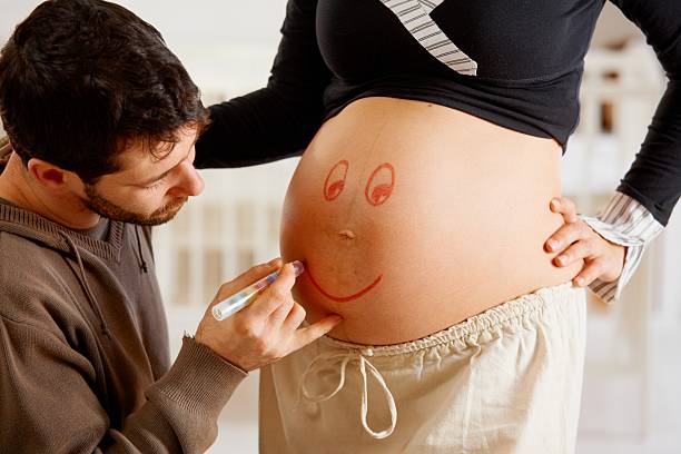 istock Husband drawing smiley face to pregnant belly 157586626