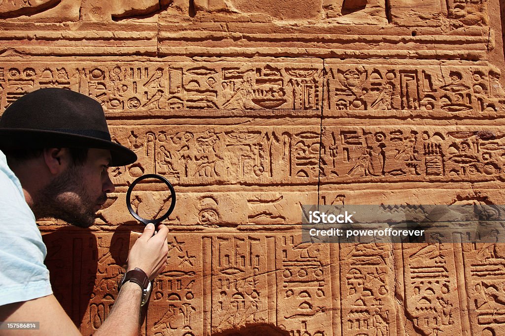 Archeologist Archeologist reading hieroglyphics with magnifying glass Hieroglyphics Stock Photo