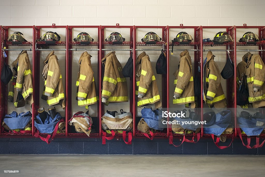 Firehouse Gear Rows of gear (jackets, pants, boots, and helmets) sit ready for firemen when needed. Fire Station Stock Photo