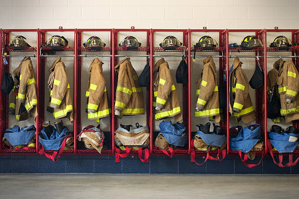 Firehouse Gear Rows of gear (jackets, pants, boots, and helmets) sit ready for firemen when needed. fire station stock pictures, royalty-free photos & images