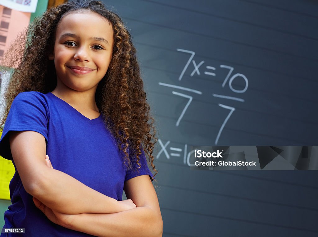 Souriant fille avec les mains pliées sur le tableau noir - Photo de Mathématiques libre de droits