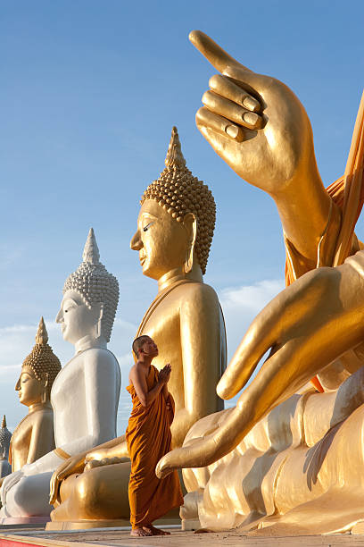 In Prayer Monk Praying To A Buddha Statue. thai traditional costume stock pictures, royalty-free photos & images