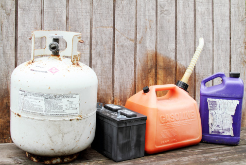 Household hazardous waste products. Gasoline container, propane gas cylinder tank, battery, and plastic chemical solvent container.