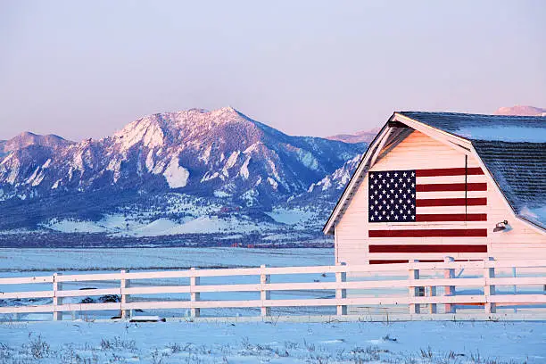 Barn with American Flag painted on side, in front of Boulder Flatirons.