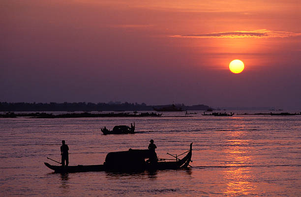 Silhouetted fishermen at sunrise on the Mekong River stock photo