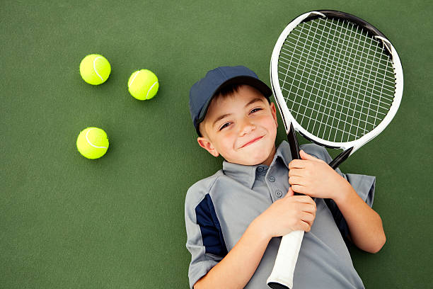 young boy y jugador de tenis acostado en la cancha de tenis - tennis child childhood sport fotografías e imágenes de stock