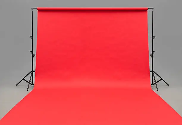 A roll of red photographic seamless background paper hung and rolled out to beyond the foreground.  Black stands on either side support the roll. Background is a gray wall/floor seamless.see#12760581 for white paper.http://www.garyalvis.com/images/conceptsIdeas.jpg