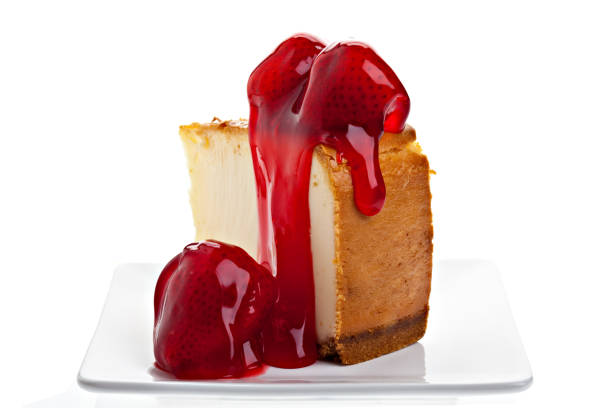 A rear view of strawberry topped New York style cheesecake on a white background. PLEASE CLICK HERE FOR MORE CHEESECAKE