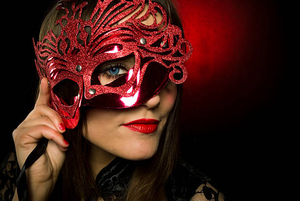 Young woman with red mask and lipstick Attractive female with blue eyes looking through the mask carnival mask women party stock pictures, royalty-free photos & images
