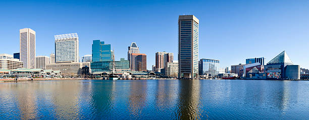 Baltimore Inner Harbor With Reflections in Early Morning - Panorama Panorama of Baltimore's Inner Harbor with numerous skyscrapers casting a reflection in the early morning sunshine. baltimore maryland stock pictures, royalty-free photos & images
