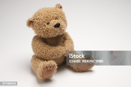 istock Light brown stuffed bear sitting on white surface 157588550