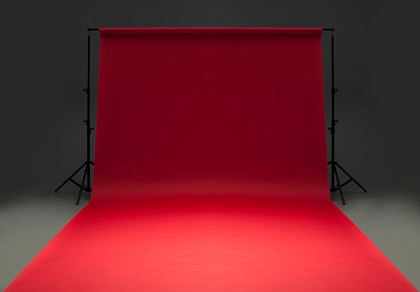 Seamless red background paper hanging on stands-isolated on grey Studio photograph of red seamless photographic background roll paper rolled out to beyond the foreground. The center of the paper is softly spot lighted to highlight the center while the rear is subdued. Red paper is set on a seamless gray background with black support stands. Room for text and subject.http://www.garyalvis.com/images/conceptsIdeas.jpg behind the scenes photos stock pictures, royalty-free photos & images