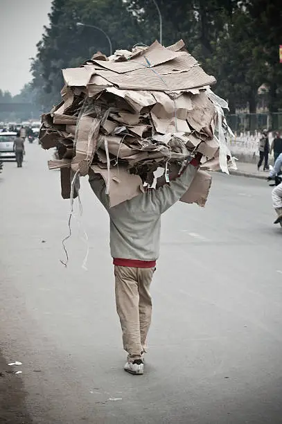 Photo of Paper recyling collector carrying heavy load down street Kathmandu Nepal