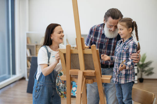 istock Lady having fun with aged dad and kid in home art space 1575889088