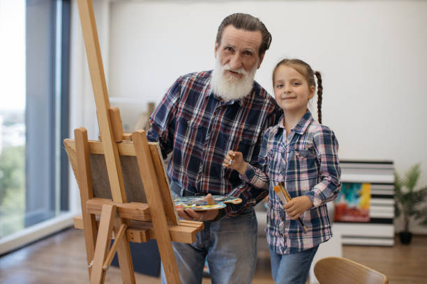 istock Senior painter rejoicing in art with granddaughter at home 1575889131