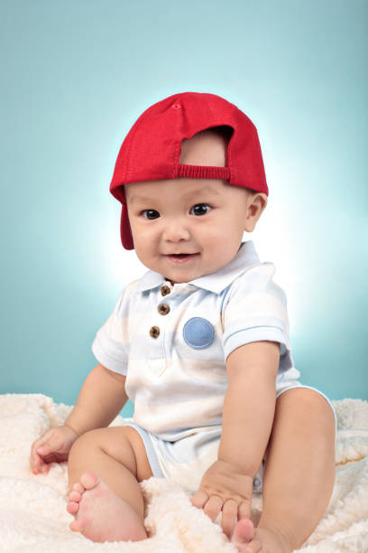 istock cute little baby boy with red cap and sitting 157588988