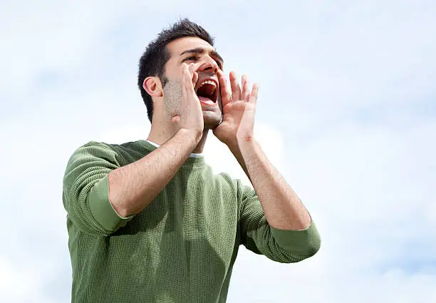 Man shouting  with hands cupped - outdoors