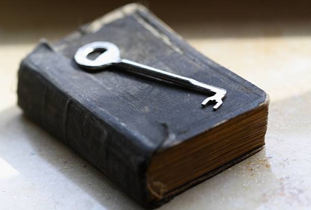 The key lying on old book / bible The key lying on old book / bible alte algarve stock pictures, royalty-free photos & images