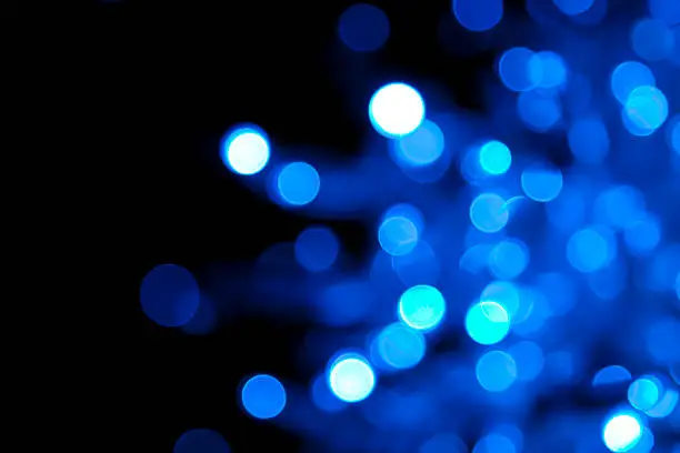 Photo of Out of focus illuminated blue dots on black background